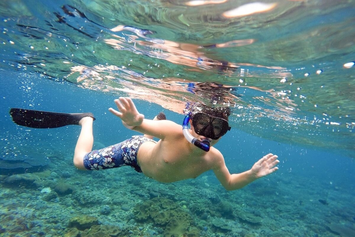 Tiener snorkelt bij rotsachtig strand